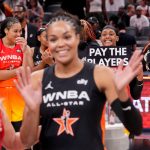 Washington Mystics' Brittney Sykes (20) holds a sign as Minnesota Lynx's Napheesa Collier (24) is interviewed Saturday, July 19, 2025, during the WNBA All-Star Game at Gainbridge Fieldhouse in Indianapolis.