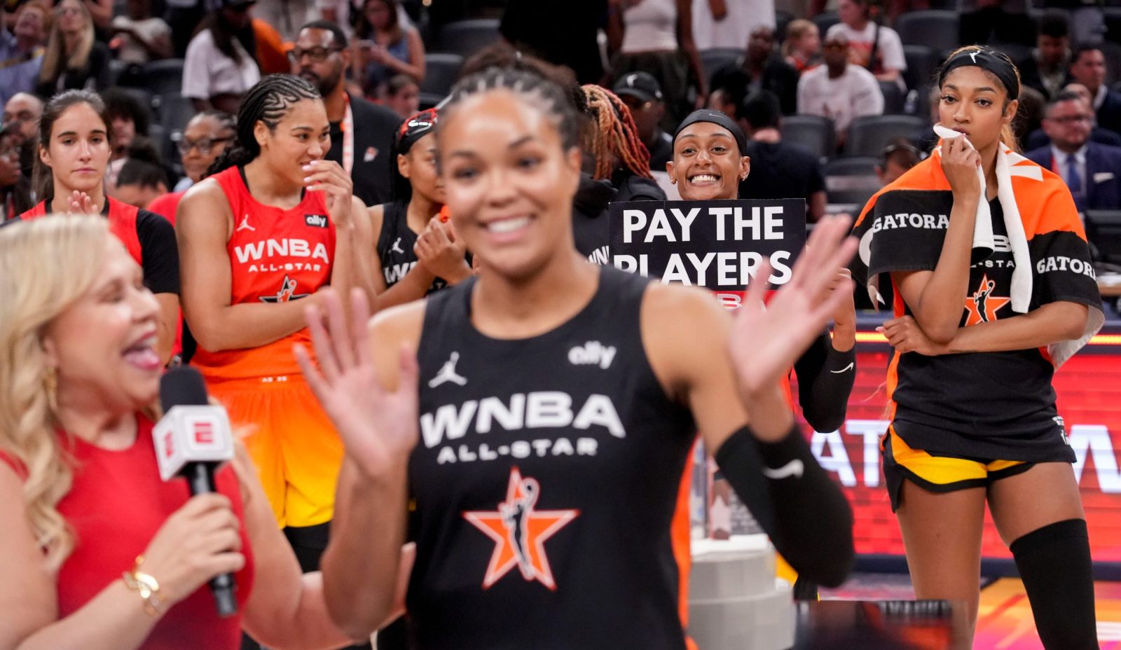Washington Mystics' Brittney Sykes (20) holds a sign as Minnesota Lynx's Napheesa Collier (24) is interviewed Saturday, July 19, 2025, during the WNBA All-Star Game at Gainbridge Fieldhouse in Indianapolis.