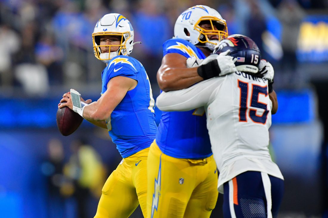 Dec 19, 2024; Inglewood, California, USA; Los Angeles Chargers quarterback Justin Herbert (10) drops back to pass as offensive tackle Rashawn Slater (70) provides coverage against Denver Broncos linebacker Nik Bonitto (15) during the second half at SoFi Stadium. Mandatory Credit: Gary A. Vasquez-Imagn Images