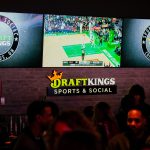 Sports are shown on TVs behind a bar as guests enjoy the grand opening of DraftKings Sports & Social in Ohio.