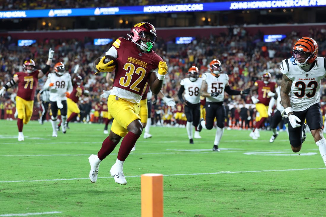 Aug 18, 2025; Landover, Maryland, USA; Washington Commanders running back Jacory Croskey-Merritt (32) scores a touchdown past Cincinnati Bengals safety Daijahn Anthony (33) during the first half at Northwest Stadium. Mandatory Credit: Amber Searls-Imagn Images
