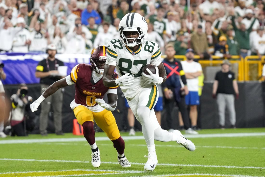 Sep 11, 2025; Green Bay, Wisconsin, USA; Green Bay Packers wide receiver Romeo Doubs (87) scores a touchdown against Washington Commanders cornerback Mike Sainristil (0) in the first quarter at Lambeau Field. Mandatory Credit: Jeff Hanisch-Imagn Images