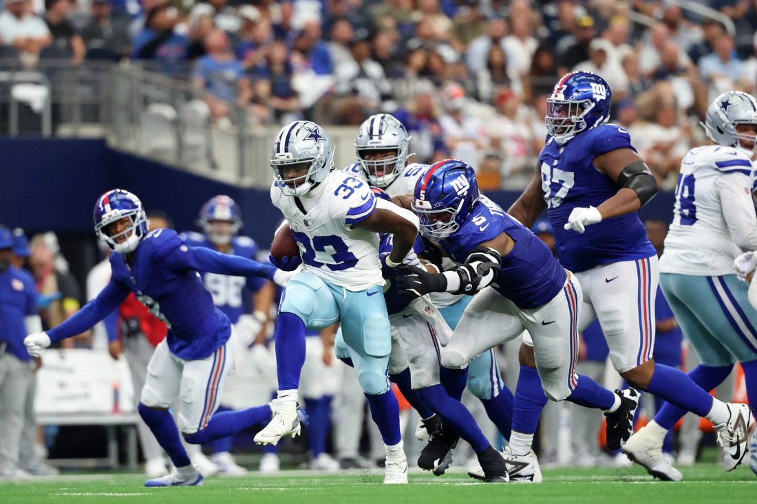Sep 14, 2025; Arlington, Texas, USA; Dallas Cowboys running back Javonte Williams (33) runs with the ball against New York Giants linebacker Kayvon Thibodeaux (5) during the third quarter at AT&T Stadium. Mandatory Credit: Kevin Jairaj-Imagn Images