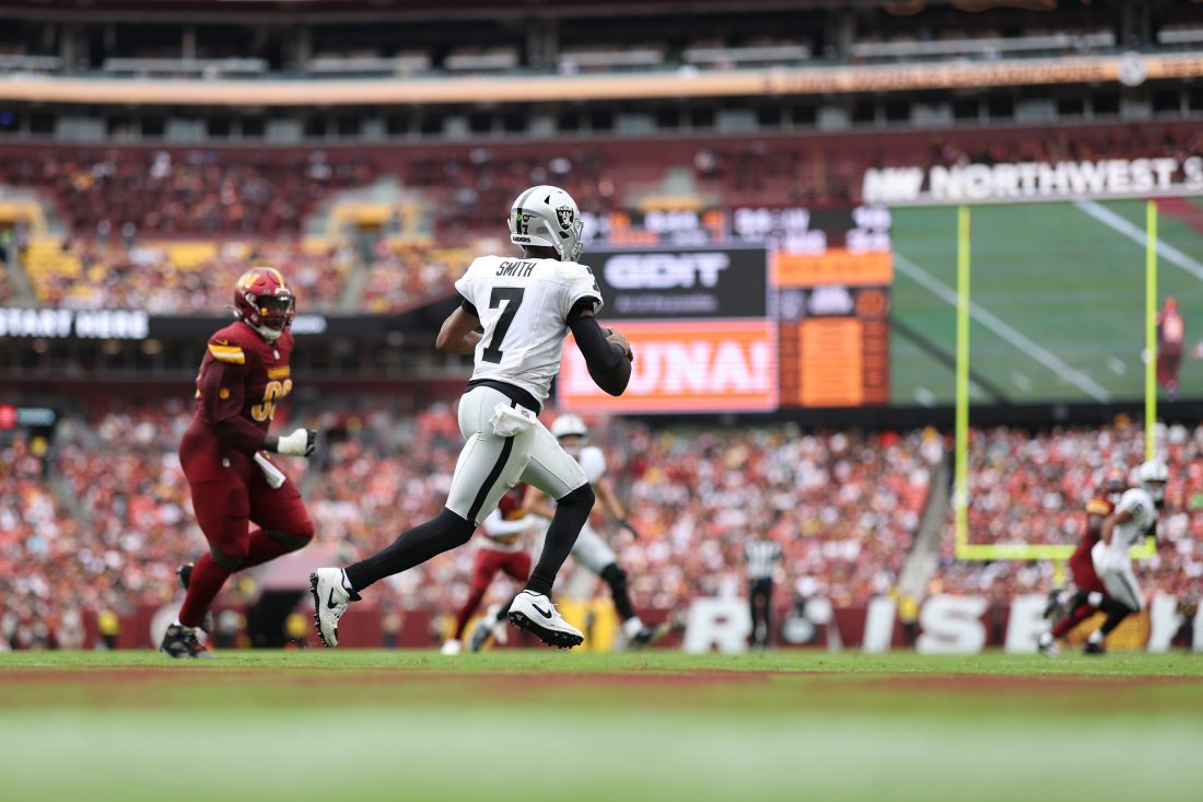 Sep 21, 2025; Landover, Maryland, USA; Las Vegas Raiders quarterback Geno Smith (7) scrambles from Washington Commanders defensive end Javontae Jean-Baptiste (90) during the fourth quarter at Northwest Stadium. Mandatory Credit: Geoff Burke-Imagn Images