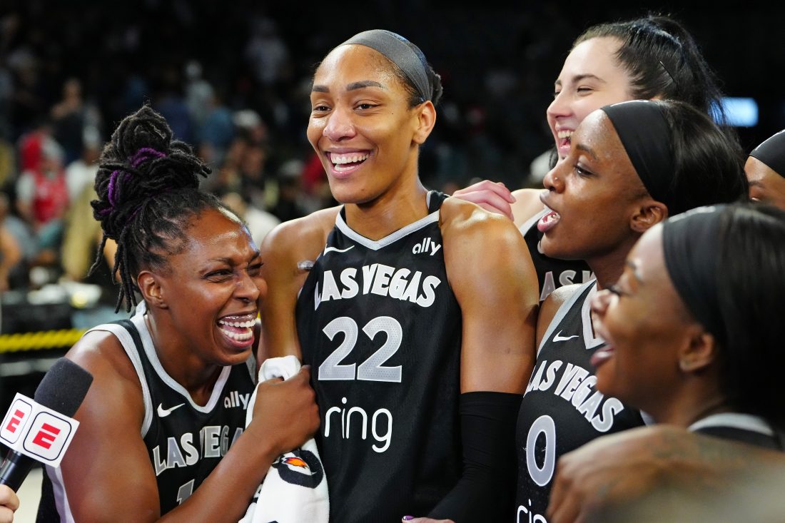 Sep 30, 2025; Las Vegas, Nevada, USA; Las Vegas Aces guard Chelsea Gray (12), Las Vegas Aces center A'ja Wilson (22), and Las Vegas Aces guard Jackie Young (0) react during an interview after defeating the Indiana Fever 107-98 in overtime of game five of the second round for the 2025 WNBA Playoffs at Michelob Ultra Arena.