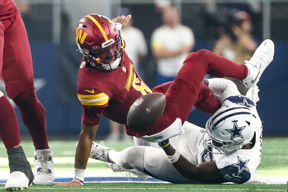 Oct 19, 2025; Arlington, Texas, USA; Washington Commanders quarterback Jayden Daniels (5) fumbles the ball defended by Dallas Cowboys linebacker Shemar James (50) during the third quarter of the game at AT&T Stadium. Mandatory Credit: Kevin Jairaj-Imagn Images
