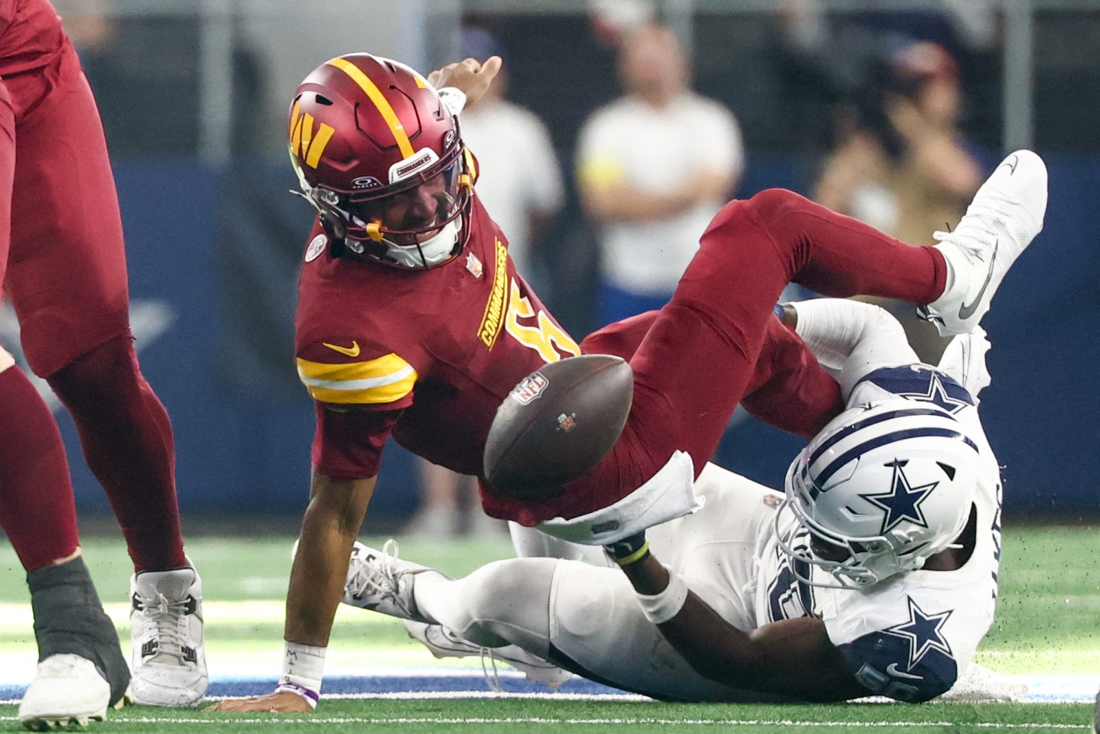 Oct 19, 2025; Arlington, Texas, USA; Washington Commanders quarterback Jayden Daniels (5) fumbles the ball defended by Dallas Cowboys linebacker Shemar James (50) during the third quarter of the game at AT&T Stadium. Mandatory Credit: Kevin Jairaj-Imagn Images