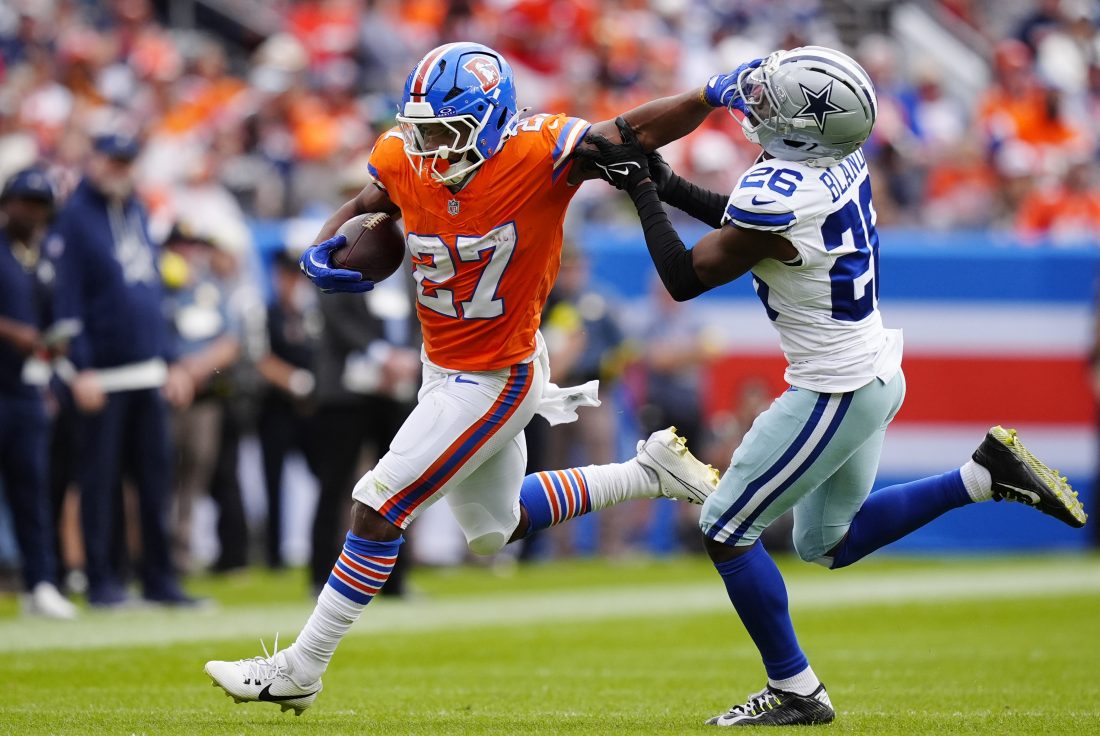 Oct 26, 2025; Denver, Colorado, USA; Denver Broncos running back J.K. Dobbins (27) runs against Dallas Cowboys cornerback DaRon Bland (26) in the first half at Empower Field at Mile High. Mandatory Credit: Ron Chenoy-Imagn Images