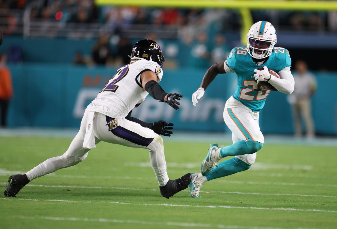 Oct 30, 2025; Miami Gardens, Florida, USA; Miami Dolphins running back De'Von Achane (28) runs for a gain past Baltimore Ravens safety Alohi Gilman (12) during the first quarter at Hard Rock Stadium. Mandatory Credit: Nathan Ray Seebeck-Imagn Images