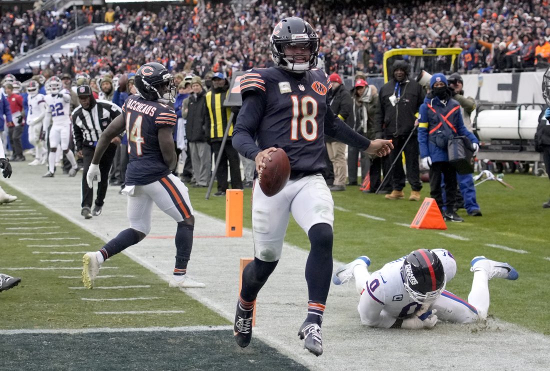 Nov 9, 2025; Chicago, Illinois, USA; Chicago Bears quarterback Caleb Williams (18) scores the game-winning touchdown against New York Giants linebacker Brian Burns (0) during the fourth quarter at Soldier Field. Mandatory Credit: David Banks-Imagn Images