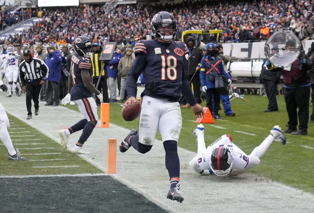 Nov 9, 2025; Chicago, Illinois, USA; Chicago Bears quarterback Caleb Williams (18) scores the game-winning touchdown against New York Giants linebacker Brian Burns (0) during the fourth quarter at Soldier Field.