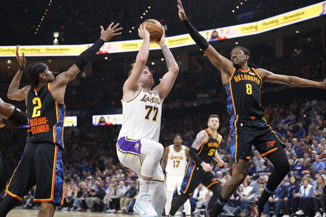 Apr 6, 2025; Oklahoma City, Oklahoma, USA; Los Angeles Lakers guard Luka Doncic (77) drives to the basket between Oklahoma City Thunder guard Shai Gilgeous-Alexander (2) and forward Jalen Williams (8) during the second quarter at Paycom Center. Mandatory Credit: Alonzo Adams-Imagn Images