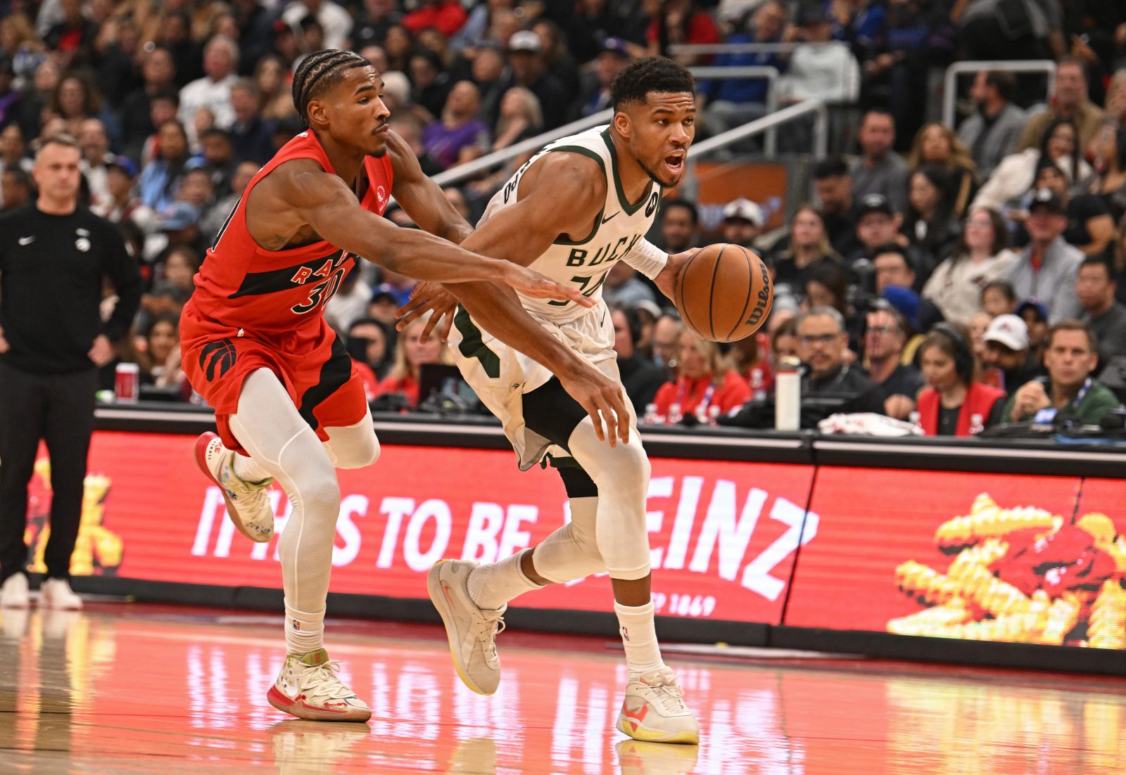 Oct 24, 2025; Toronto, Ontario, CAN; Milwaukee Bucks forward Giannis Antetokounmpo (34) dribbles past Toronto Raptors guard Ochai Agbaji (30) in the second quarter at Scotiabank Arena. Mandatory Credit: Gerry Angus-Imagn Images