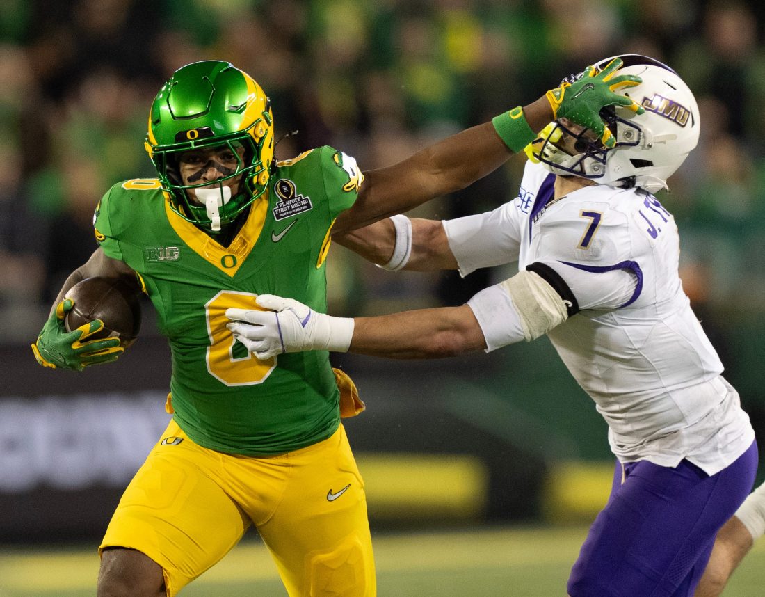 Oregon’s Jordon Davison, left, stiff arms James Madison’s Jacob Thomas for a gain during the second quarter Autzen Stadium in Eugene Dec. 20, 2025.