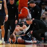 Dec 29, 2025; Miami, Florida, USA; Denver Nuggets center Nikola Jokic (15) grabs his left knee as head coach David Adelman approaches him after an injury against the Miami Heat during the second quarter at Kaseya Center. Mandatory Credit: Sam Navarro-Imagn Images