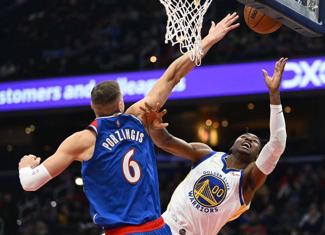 Mar 27, 2022; Washington, District of Columbia, USA; Golden State Warriors forward Jonathan Kuminga (00) shoots as Washington Wizards center Kristaps Porzingis (6) defends during the first half at Capital One Arena. Mandatory Credit: Brad Mills-USA TODAY Sports