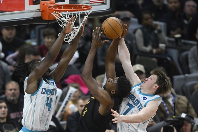 Dec 14, 2025; Cleveland, Ohio, USA; Cleveland Cavaliers forward De'Andre Hunter (12) shoots between Charlotte Hornets guard Sion James (4) and guard Kon Knueppel (7) in the fourth quarter at Rocket Arena. Mandatory Credit: David Richard-Imagn Images