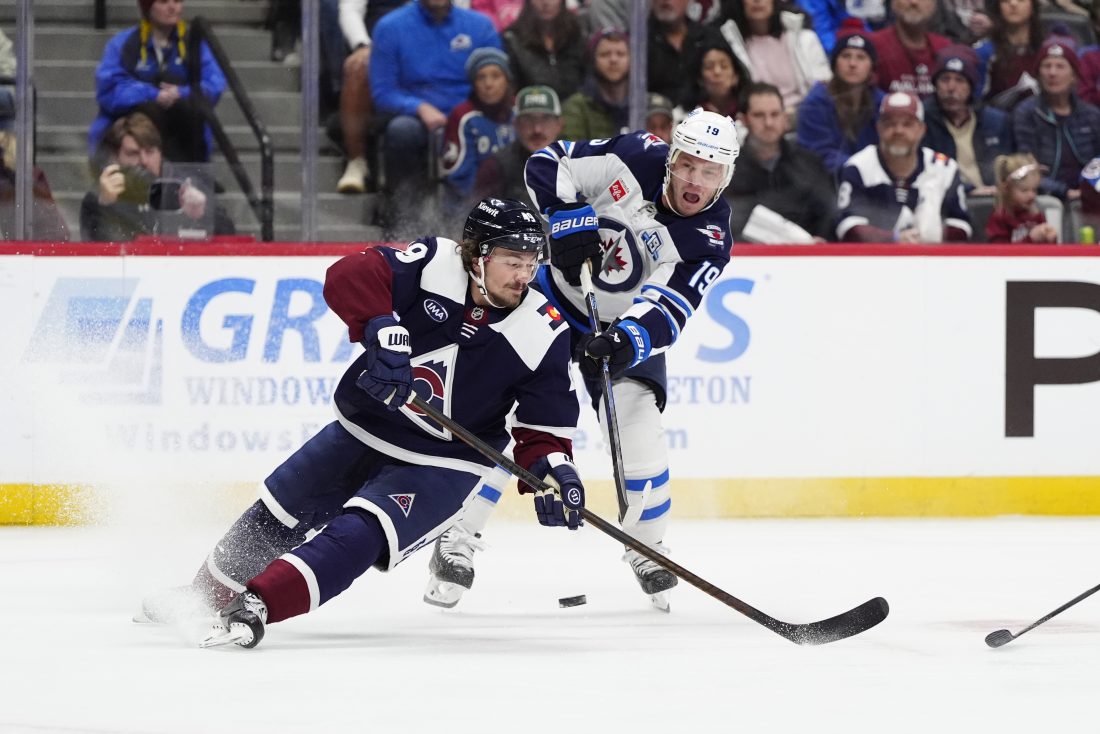 Dec 19, 2025; Denver, Colorado, USA; Winnipeg Jets center Jonathan Toews (19) shoot the puck past Colorado Avalanche defenseman Samuel Girard (49) in the first period at Ball Arena. Mandatory Credit: Ron Chenoy-Imagn Images