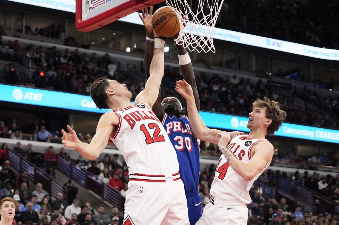 Dec 26, 2025; Chicago, Illinois, USA; Chicago Bulls forward Zach Collins (12) defends Philadelphia 76ers center Adem Bona (30) during the second half at United Center.
