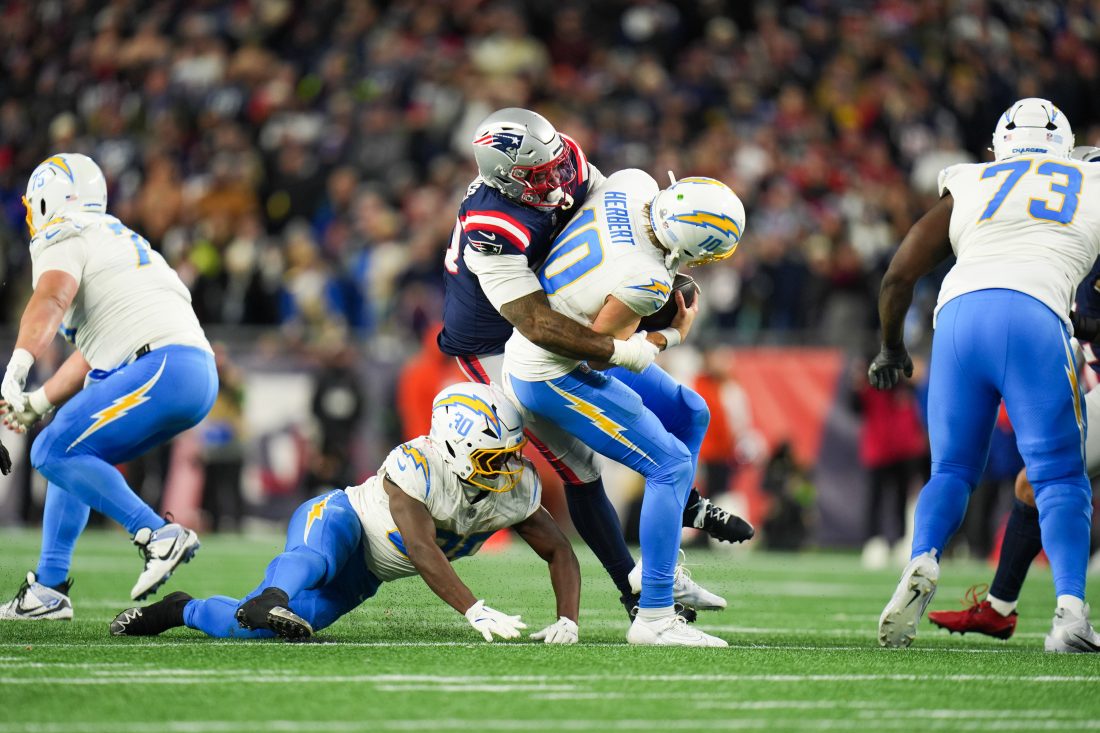 an 11, 2026; Foxborough, MA, USA; Los Angeles Chargers quarterback Justin Herbert (10) is sacked by New England Patriots linebacker Anfernee Jennings (33) during the fourth quarter against the New England Patriotsin an AFC Wild Card Round game at Gillette Stadium.