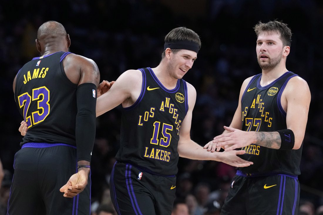 Nov 18, 2025; Los Angeles, California, USA; Los Angeles Lakers guard Austin Reaves (15) is congratulated by forward LeBron James (23) and guard Luka Doncic (77) after a three-point basket in the second quarter at Crypto.com Arena.