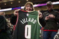 Jan 31, 2024; Portland, Oregon, USA; A basketball fan holds a jersey with the colors and number of the Portland Trail Blazers and Milwaukee Bucks guard Damian Lillard (0) at Moda Center. Mandatory Credit: Troy Wayrynen-USA TODAY Sports