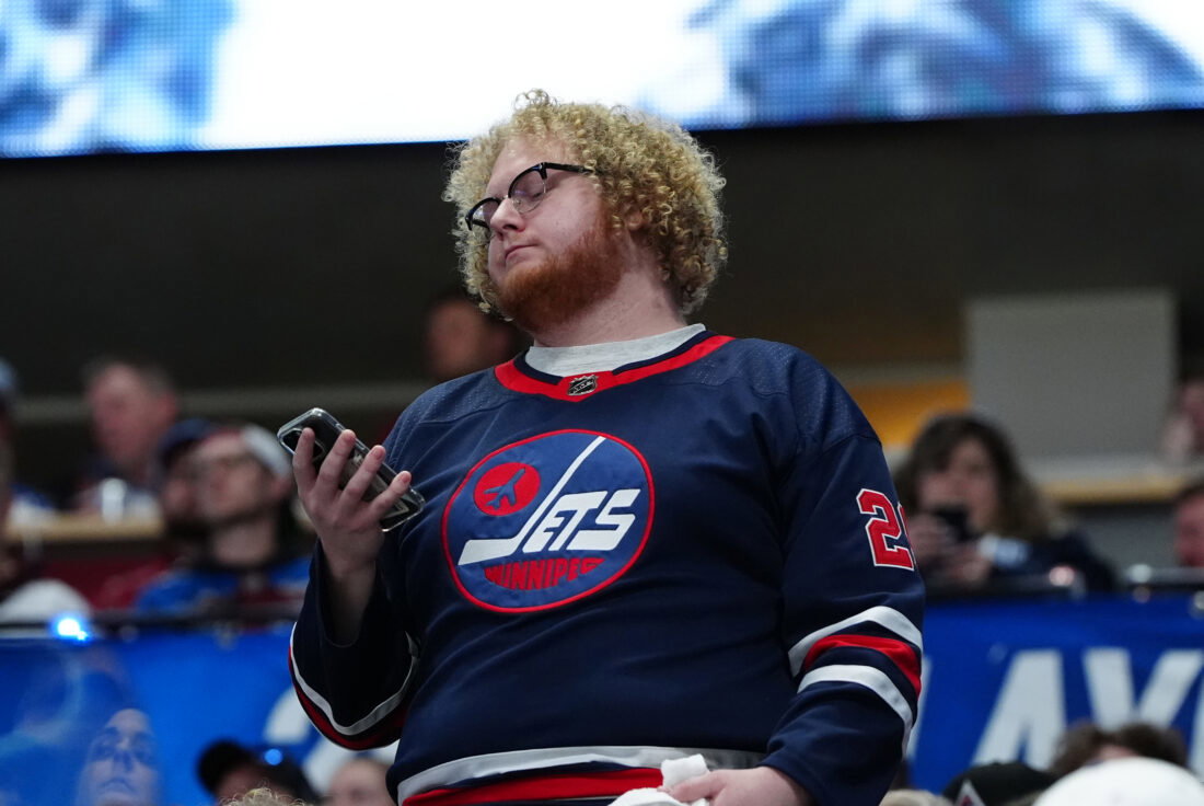 Apr 28, 2024; Denver, Colorado, USA; Winnipeg Jets fan checks his phone during the first period against the Colorado Avalanche in game four of the first round of the 2024 Stanley Cup Playoffs at Ball Arena. Mandatory Credit: Ron Chenoy-USA TODAY Sports