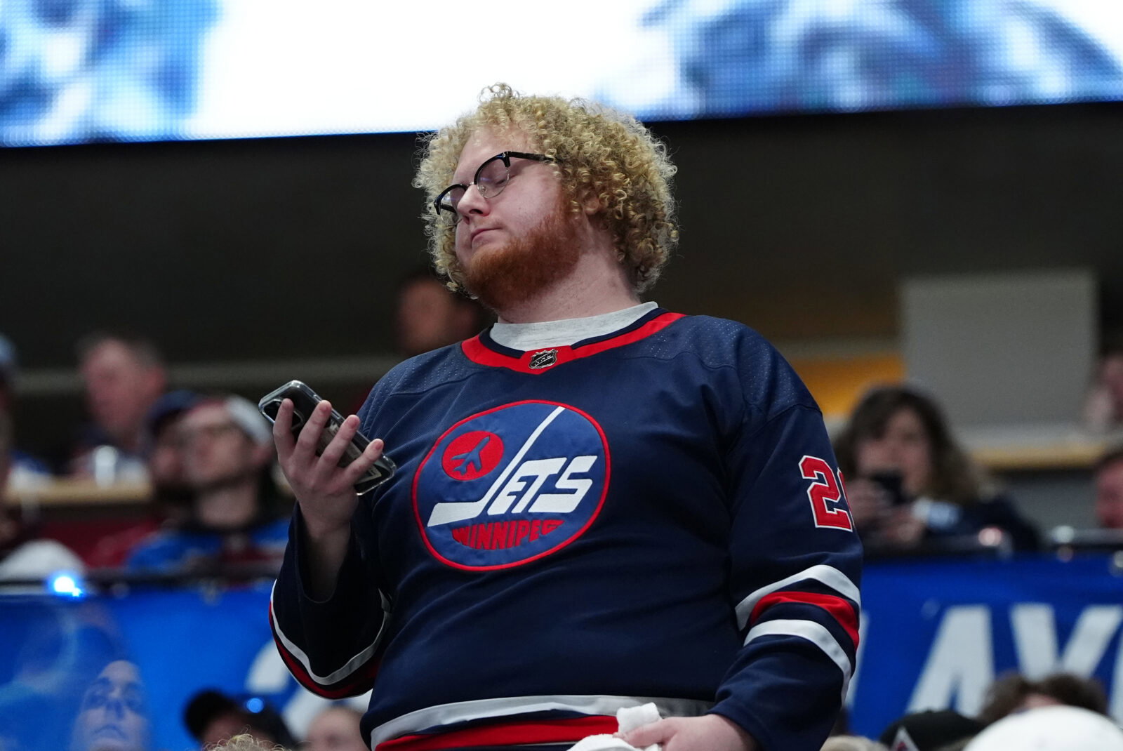 Apr 28, 2024; Denver, Colorado, USA; Winnipeg Jets fan checks his phone during the first period against the Colorado Avalanche in game four of the first round of the 2024 Stanley Cup Playoffs at Ball Arena. Mandatory Credit: Ron Chenoy-USA TODAY Sports