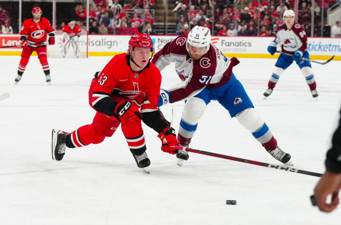 Dec 5, 2024; Raleigh, North Carolina, USA; Colorado Avalanche right wing Nikolai Kovalenko (51) checks Carolina Hurricanes right wing Jackson Blake (53) during the third period at Lenovo Center. Mandatory Credit: James Guillory-Imagn Images