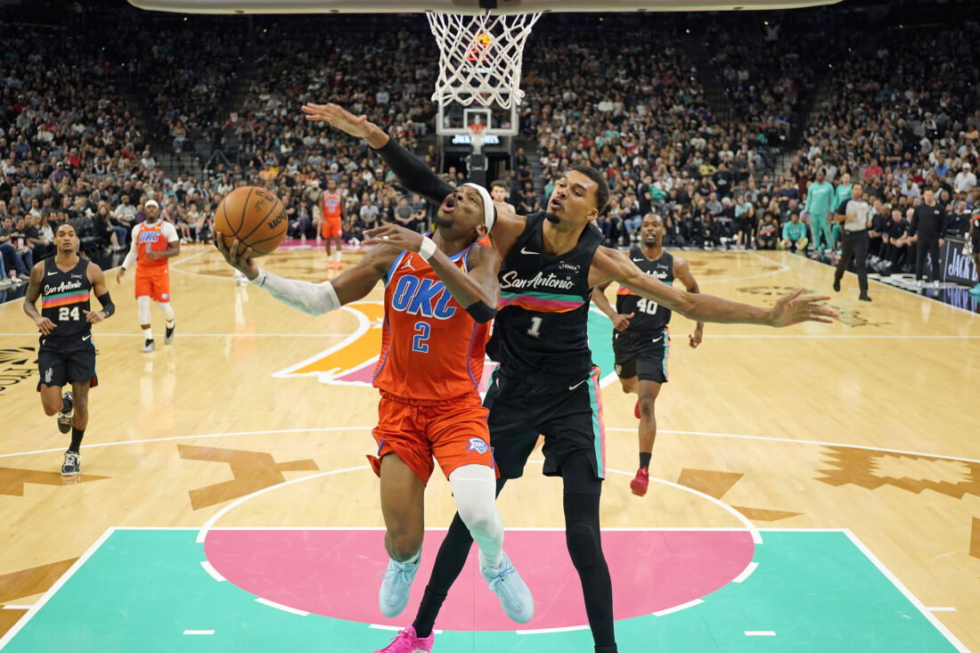 Dec 23, 2025; San Antonio, Texas, USA; Oklahoma City Thunder guard Shai Gilgeous-Alexander (2) drives to the basket past San Antonio Spurs forward Victor Wembanyama (1) during the first half at Frost Bank Center. Mandatory Credit: Scott Wachter-Imagn Images