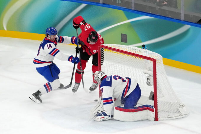 Feb 22, 2026; Milan, Italy; Connor McDavid of Canada battles for the puck against Brock Faber and Connor Hellebuyck of the United States during the men's ice hockey gold medal game during the Milano Cortina 2026 Olympic Winter Games at Milano Santagiulia Ice Hockey Arena. Mandatory Credit: James Lang-Imagn Images