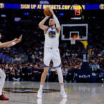 Mar 29, 2026; Denver, Colorado, USA; Golden State Warriors center Kristaps Porzingis (7) attempts a shot as Denver Nuggets guard Julian Strawther (3) defends in the second quarter at Ball Arena.