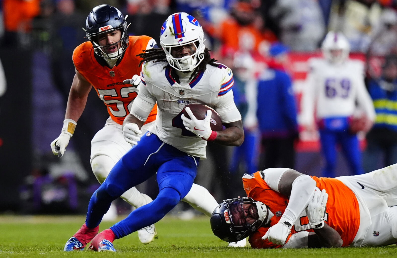 Jan 17, 2026; Denver, CO, USA; Buffalo Bills running back James Cook III (4) runs against Denver Broncos linebacker Jonah Elliss (52) and defensive end Eyioma Uwazurike (96) during the fourth quarter of an AFC Divisional Round playoff game at Empower Field at Mile High. Mandatory Credit: