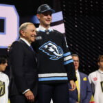 Jun 26, 2026; Buffalo, New York, USA; Ethan Belchetz reacts beside NHL commissioner Gary Bettman after being selected with the seventeenth pick in the first round of the 2026 NHL Draft by the Utah Mammoth at KeyBank Center. Mandatory Credit: Timothy T. Ludwig-Imagn Images