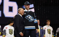 Jun 26, 2026; Buffalo, New York, USA; Ethan Belchetz reacts beside NHL commissioner Gary Bettman after being selected with the seventeenth pick in the first round of the 2026 NHL Draft by the Utah Mammoth at KeyBank Center. Mandatory Credit: Timothy T. Ludwig-Imagn Images