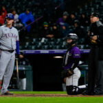May 18, 2026; Denver, Colorado, USA; Texas Rangers pinch hitter Joc Pederson (3) watches the video board with Colorado Rockies catcher Hunter Goodman (15) and home plate umpire John Tumpane (74) after challenging a pitch call in the seventh inning at Coors Field. Mandatory Credit: Isaiah J. Downing-Imagn Images