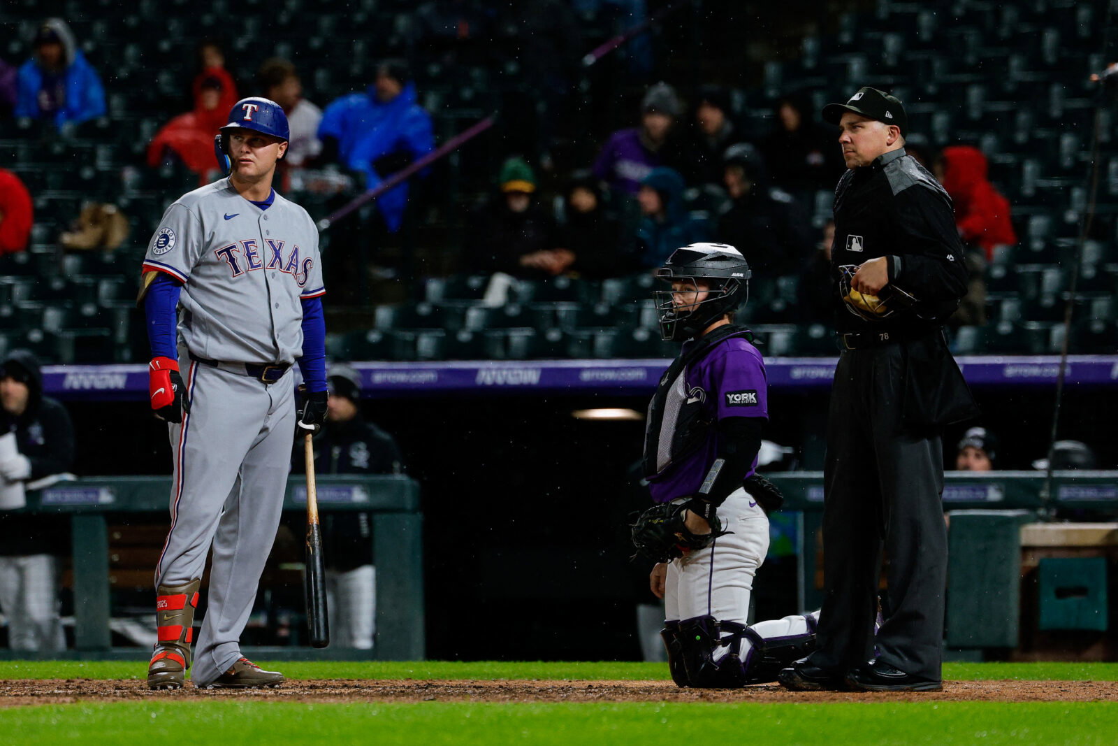 May 18, 2026; Denver, Colorado, USA; Texas Rangers pinch hitter Joc Pederson (3) watches the video board with Colorado Rockies catcher Hunter Goodman (15) and home plate umpire John Tumpane (74) after challenging a pitch call in the seventh inning at Coors Field. Mandatory Credit: Isaiah J. Downing-Imagn Images