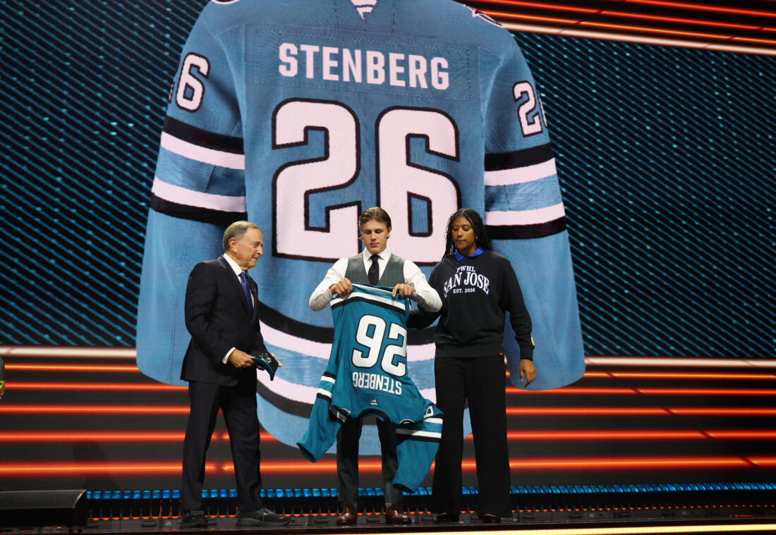 Jun 26, 2026; Buffalo, New York, USA; Ivar Stenberg puts on a San Jose Sharks sweater beside NHL commissioner Gary Bettman after being selected with the second pick in the first round of the 2026 NHL Draft at KeyBank Center. Mandatory Credit: Timothy T. Ludwig-Imagn Images