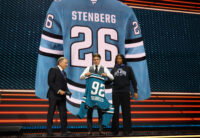 Jun 26, 2026; Buffalo, New York, USA; Ivar Stenberg puts on a San Jose Sharks sweater beside NHL commissioner Gary Bettman after being selected with the second pick in the first round of the 2026 NHL Draft at KeyBank Center. Mandatory Credit: Timothy T. Ludwig-Imagn Images