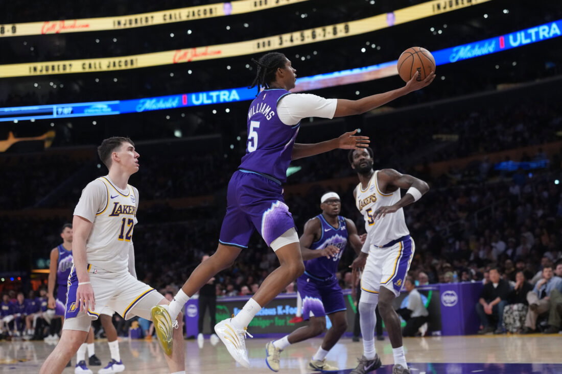 Apr 12, 2026; Los Angeles, California; Utah Jazz forward Cody Williams (5) shoots the ball against Los Angeles Lakers forward Jake LaRavia (12) and center Deandre Ayton (5) in the second half at Crypto.com Arena. Mandatory Credit: Kirby Lee-Imagn Images