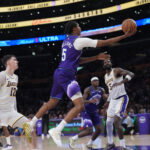 Apr 12, 2026; Los Angeles, California; Utah Jazz forward Cody Williams (5) shoots the ball against Los Angeles Lakers forward Jake LaRavia (12) and center Deandre Ayton (5) in the second half at Crypto.com Arena. Mandatory Credit: Kirby Lee-Imagn Images