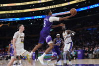 Apr 12, 2026; Los Angeles, California; Utah Jazz forward Cody Williams (5) shoots the ball against Los Angeles Lakers forward Jake LaRavia (12) and center Deandre Ayton (5) in the second half at Crypto.com Arena. Mandatory Credit: Kirby Lee-Imagn Images