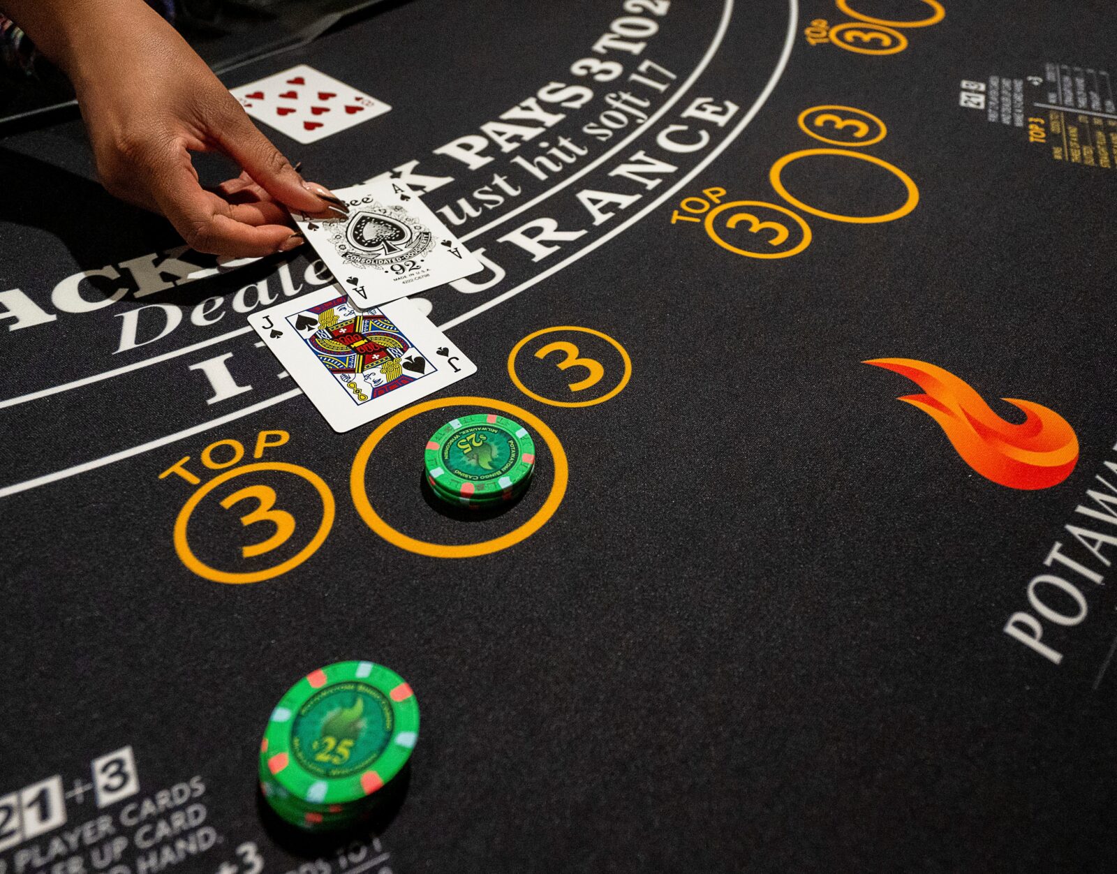 A table games dealer places cards on a blackjack table.