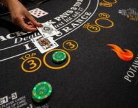 A table games dealer places cards on a blackjack table.