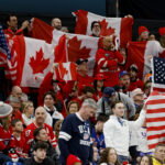 Feb 22, 2026; Milan, Italy; Canada and United States fans wave flags in the men's ice hockey gold medal game during the Milano Cortina 2026 Olympic Winter Games at Milano Santagiulia Ice Hockey Arena. Mandatory Credit: Geoff Burke-Imagn Images