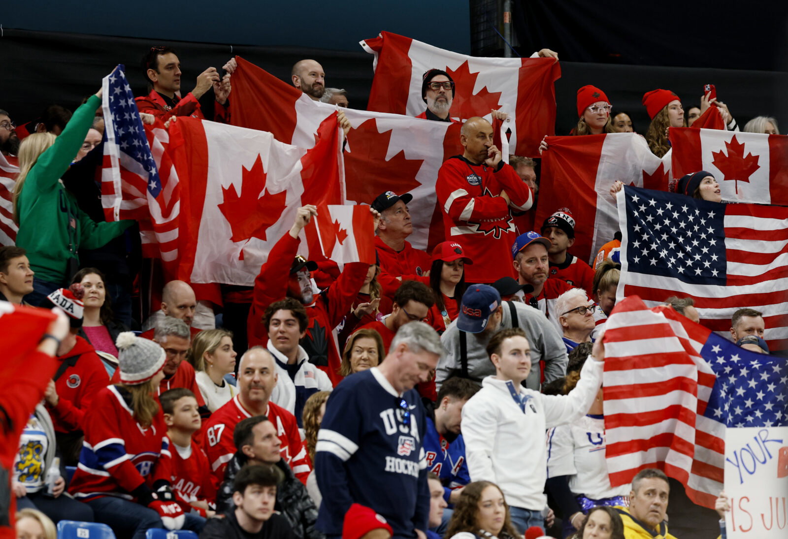 Feb 22, 2026; Milan, Italy; Canada and United States fans wave flags in the men's ice hockey gold medal game during the Milano Cortina 2026 Olympic Winter Games at Milano Santagiulia Ice Hockey Arena. Mandatory Credit: Geoff Burke-Imagn Images