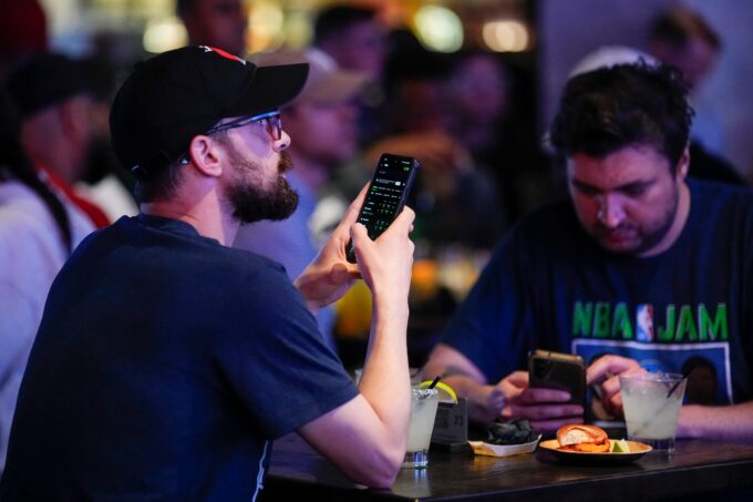 May 9, 2024; Columbus, OH, USA; Alex Bucci, left, of Worthington and Richard Mettke of German Village use the DraftKings app during the grand opening of DraftKings Sports & Social in the Short North. Though there are no on-site betting windows, eligible customers can place bets through the DraftKings app.