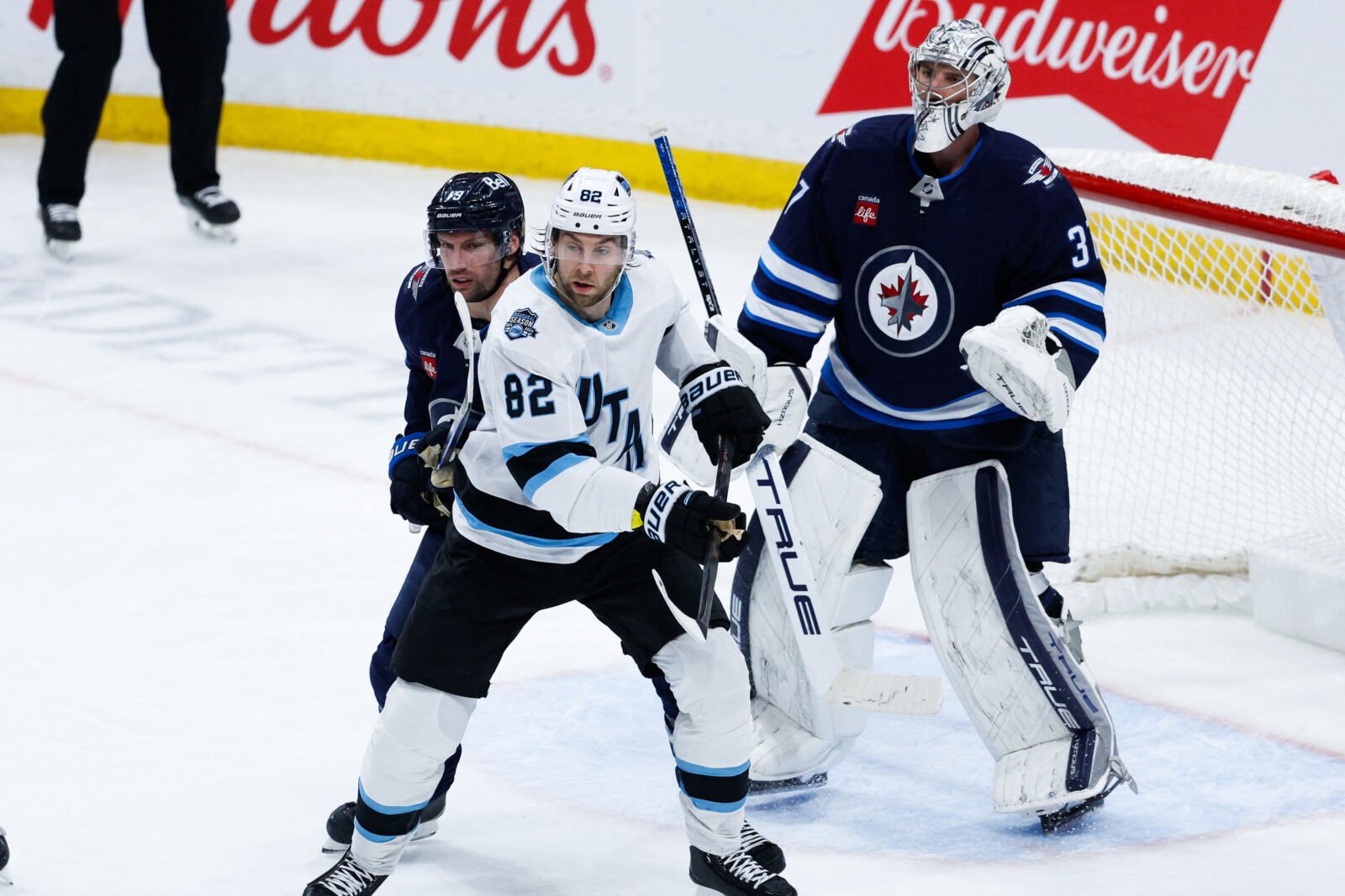 Jan 24, 2025; Winnipeg, Manitoba, CAN; Winnipeg Jets forward David Gustafsson (19) jostles for position with Utah Hockey Club forward Kevin Stenlund (82) in front of Winnipeg Jets goalie Connor Hellebuyck (37) during the third period at Canada Life Centre. Mandatory Credit: Terrence Lee-Imagn Images