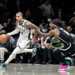 Dec 14, 2025; Brooklyn, New York, USA; Milwaukee Bucks forward Kyle Kuzma (18) drives past Brooklyn Nets guard Terance Mann (14) during the first half at Barclays Center. Mandatory Credit: John Jones-Imagn Images
