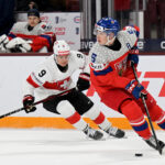 Jan 2, 2026; Minneapolis, Minnesota, USA; Czechia defensemen Adam Jiricek (5) controls the puck as Switzerland forward Nolan Cattin (9) gives chase during the first period in the quarterfinals of the 2026 IIHF World Junior Championship at 3M Arena. Mandatory Credit: Nick Wosika-Imagn Images